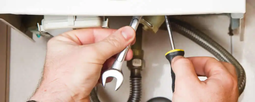 Boiler repair technician tightening pipe fittings and connections in Sacramento, CA