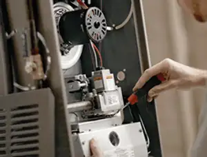 Furnace repair technician inspecting internal components and wiring in Sacramento, CA