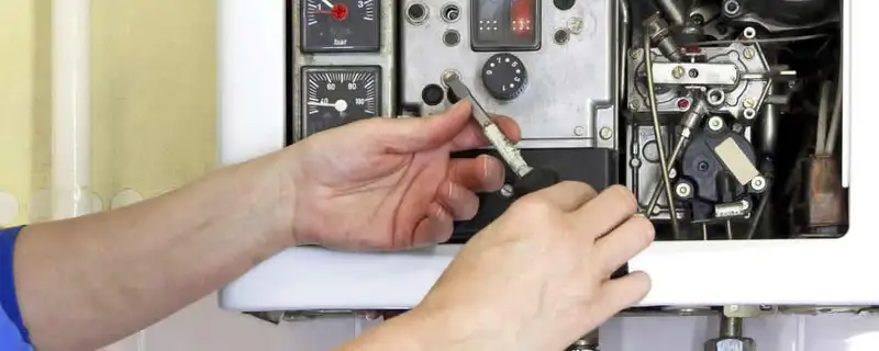 Heating repair technician adjusting boiler controls and components in Sacramento, CA