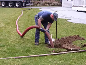 Septic pumping technician servicing a residential septic tank with a vacuum hose in Sacramento, CA