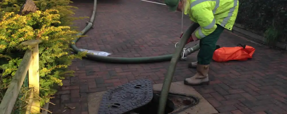 Septic tank cleaning technician servicing a septic tank with a vacuum hose in Sacramento, CA