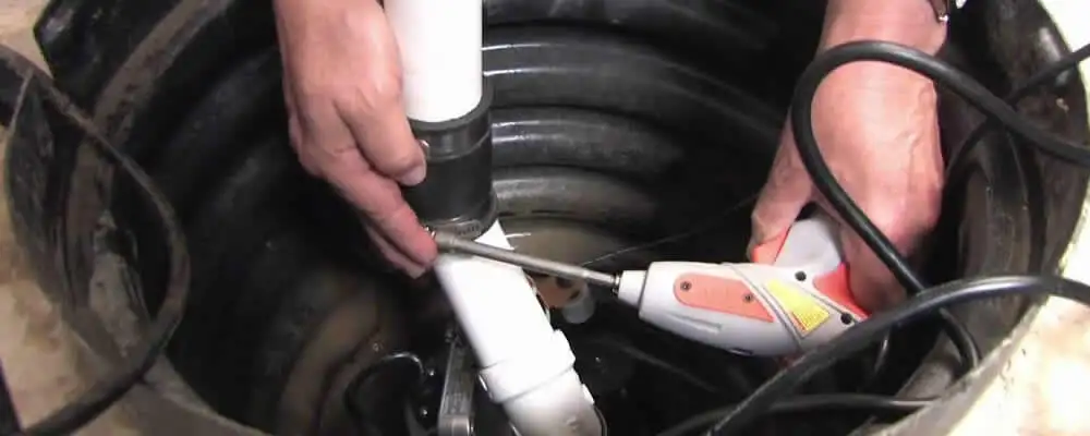 Sump pump installation technician connecting PVC discharge piping in Sacramento, CA