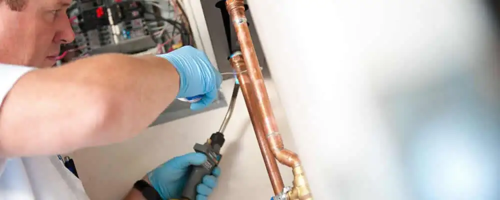 Water heater repair technician testing copper pipe connections and controls in Sacramento, CA